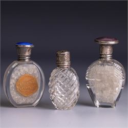 Three silver topped scent bottles, comprising cut glass example with pink guilloche enamel...