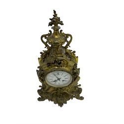 French - late 19th century 8-day gilt brass mantle clock surmounted by an urn, with a waisted case and baroque decoration raised on four splayed feet, with a glazed bezel, enamel dial with Roman numerals, five minute Arabic's and gothic steel hands, count wheel striking movement, striking the hours and half-hours on a bell. With pendulum.