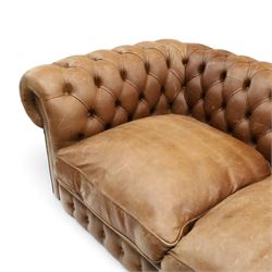Fleming & Howland Ltd - large traditional shape four seater chesterfield club sofa, the rolled ack and arms with studwork, upholstered in buttoned tan leather with loose seat cushions, raised on large turned feet