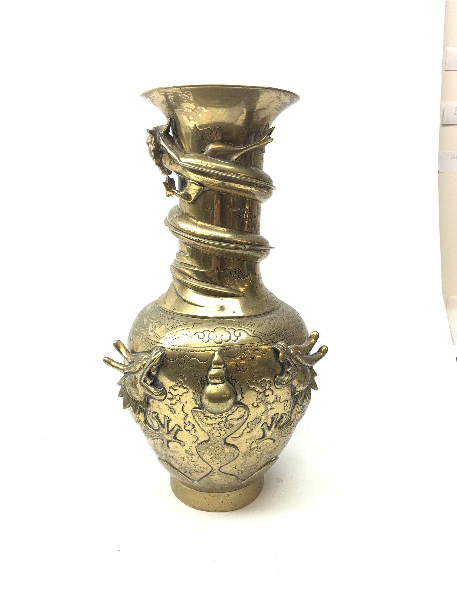 A large Chinese brass vase, of ovoid form with tall neck and flared rim, decorated in relief with dragons chasing a flaming pearl, and further incised with clouds and other detail, the base with relief dragon detail and character mark, H41