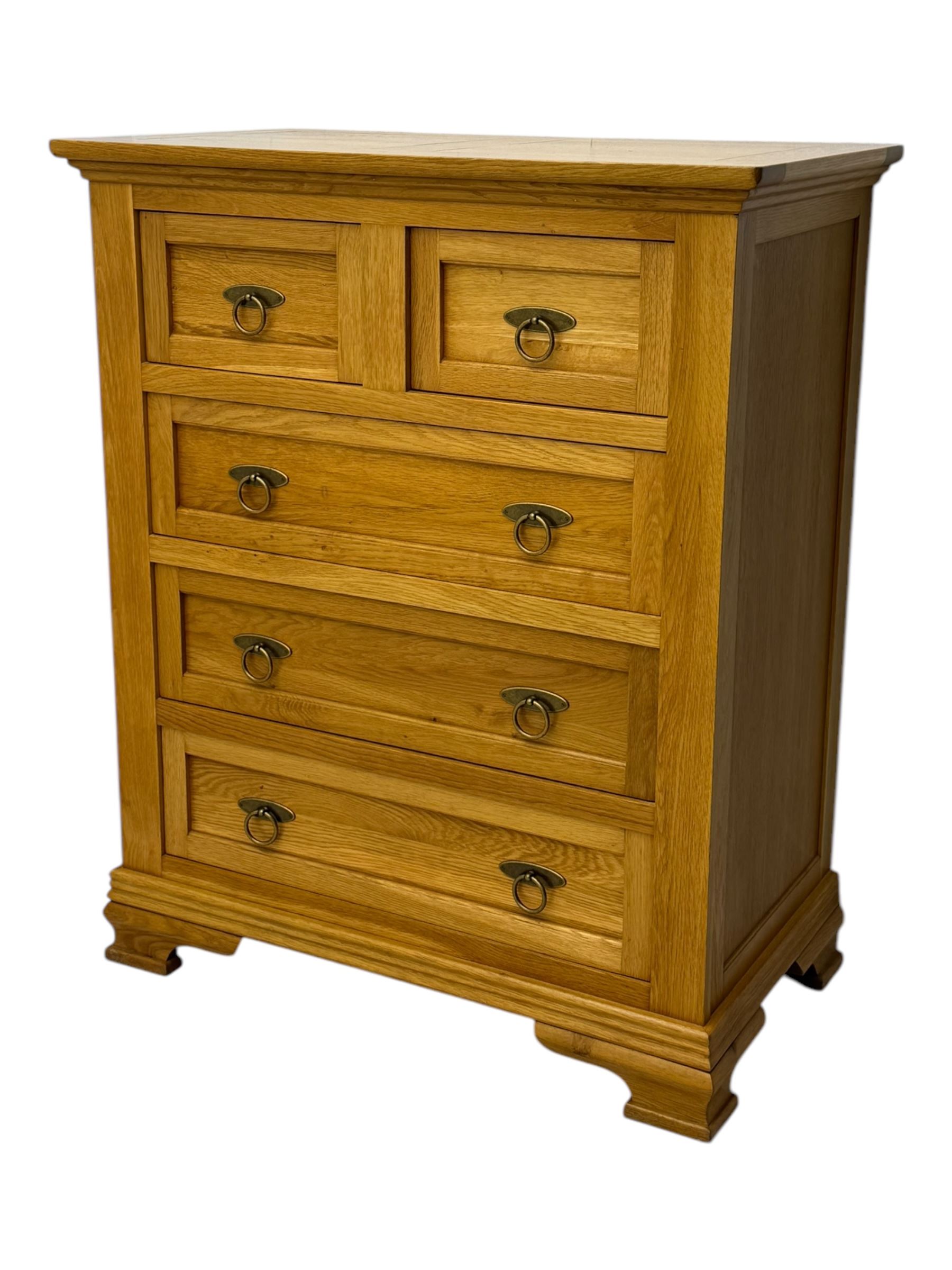 Frank Hudson - contemporary light oak chest, rectangular moulded top over two short and three long drawers, brass oval backplates with circular drop handles, on a moulded plinth base with bracket feet