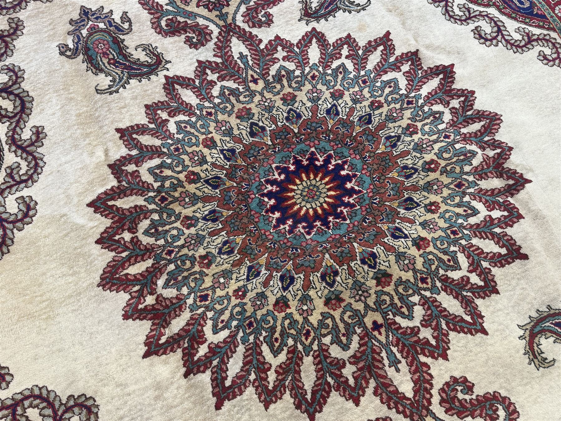 Northwest Persian signed Tabriz ivory ground carpet, central medallion with intricate floral motifs, the field and spandrels decorated with scrolling tendrils and palmettes, ivory main border with crimson and indigo floral decorations, surrounded by crimson guard bands