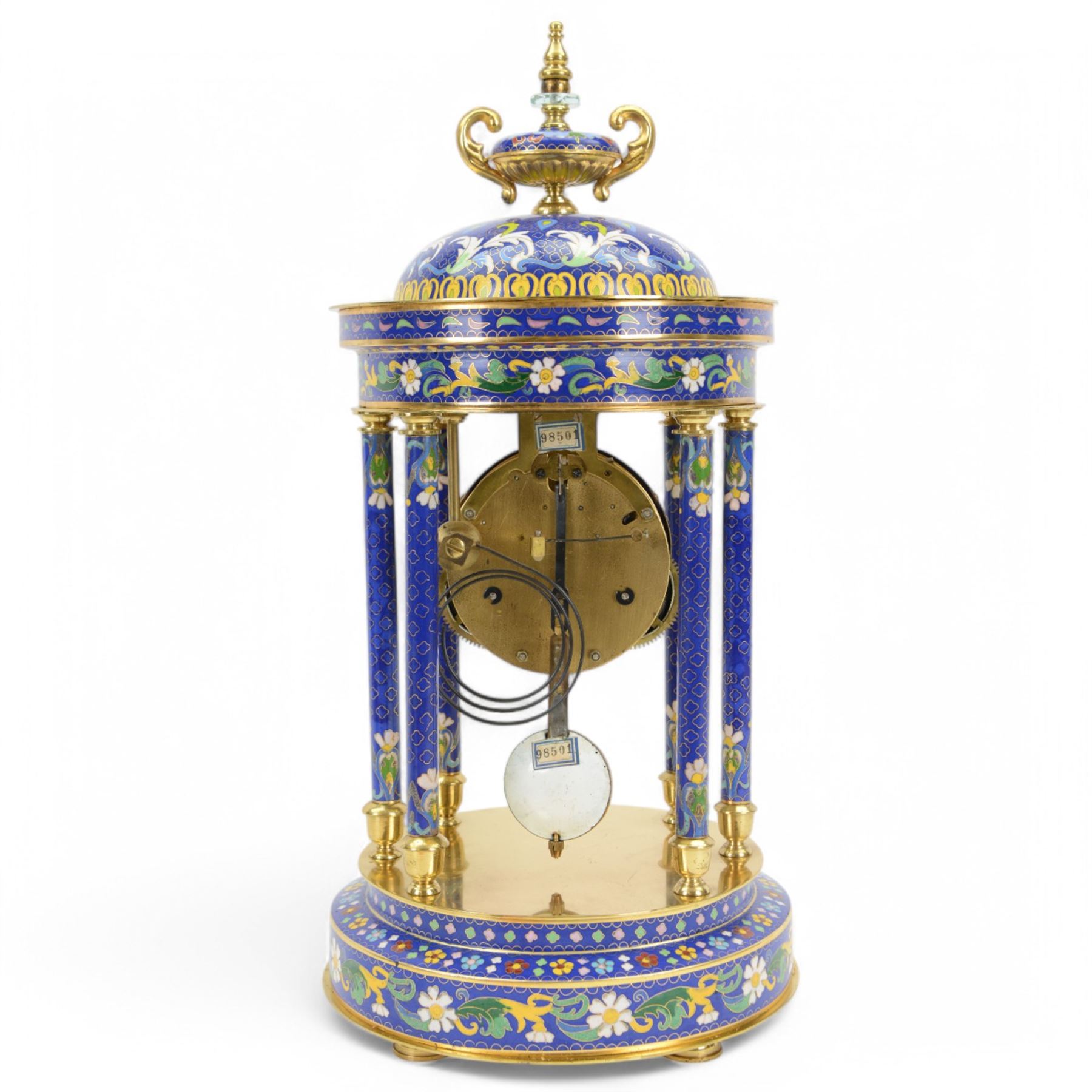 20th century- 8-day cloisonne styled rotunda clock, with six decorative enamel pillars and floral decoration to the base and top, visible pendulum with a portrait depiction of a young lady, four inch enamel dial with Roman numerals, minute markers and trefoil steel hands, twin train spring driven rack striking movement sounding the hours and half hours on a coiled gong.   