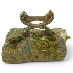 19th century cast iron boot scraper, with scrolled upright mounts, set into a rectangular moss-covered stone base