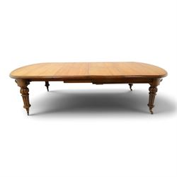Large Victorian oak extending dining table, the rectangular top with rounded corners and moulded edge, plain frieze over large turned lobed and fluted supports terminating to brass cups and castors, with two additional leaves