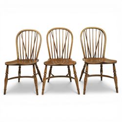 Traditional elm and beech Windsor dining chairs, each with hoop back and turned spindles over a shaped solid seat fitted with loose floral upholstered cushions, raised on turned tapering supports united by crinoline stretchers