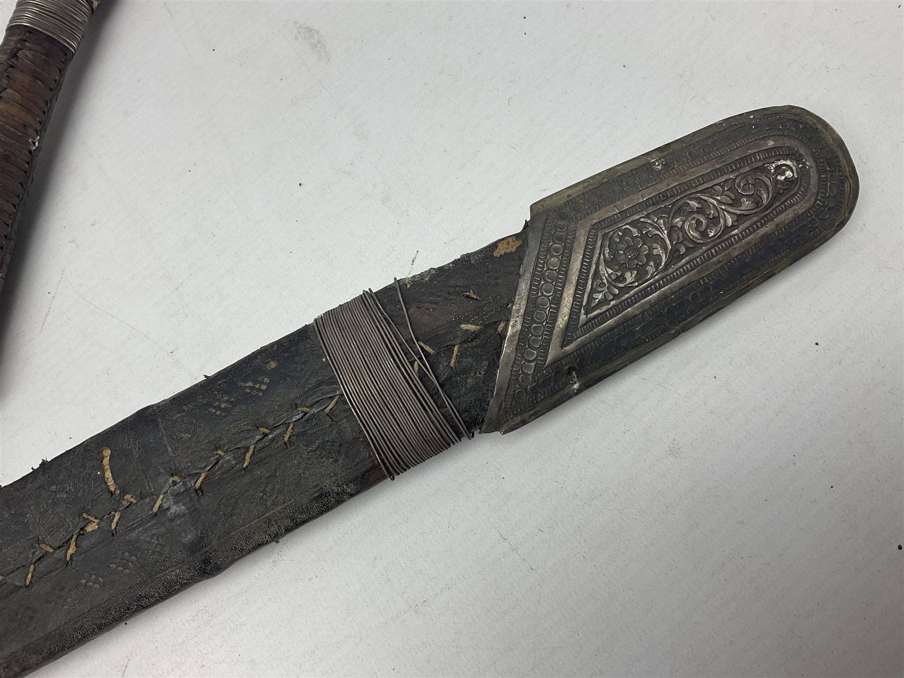 Omani presentation sword kattara, with 77cm  broad slightly curved single edge blade with two fullers, leather bound hilt woven with silver wire decoration and iron pommel;  in tooled leather scabbard with chased silver mounts and presentation plaque 'To Capt. D.M. Naylor From C Company NFR Oman Dec 1962' (Northern Frontier Regiment) L99cm overall