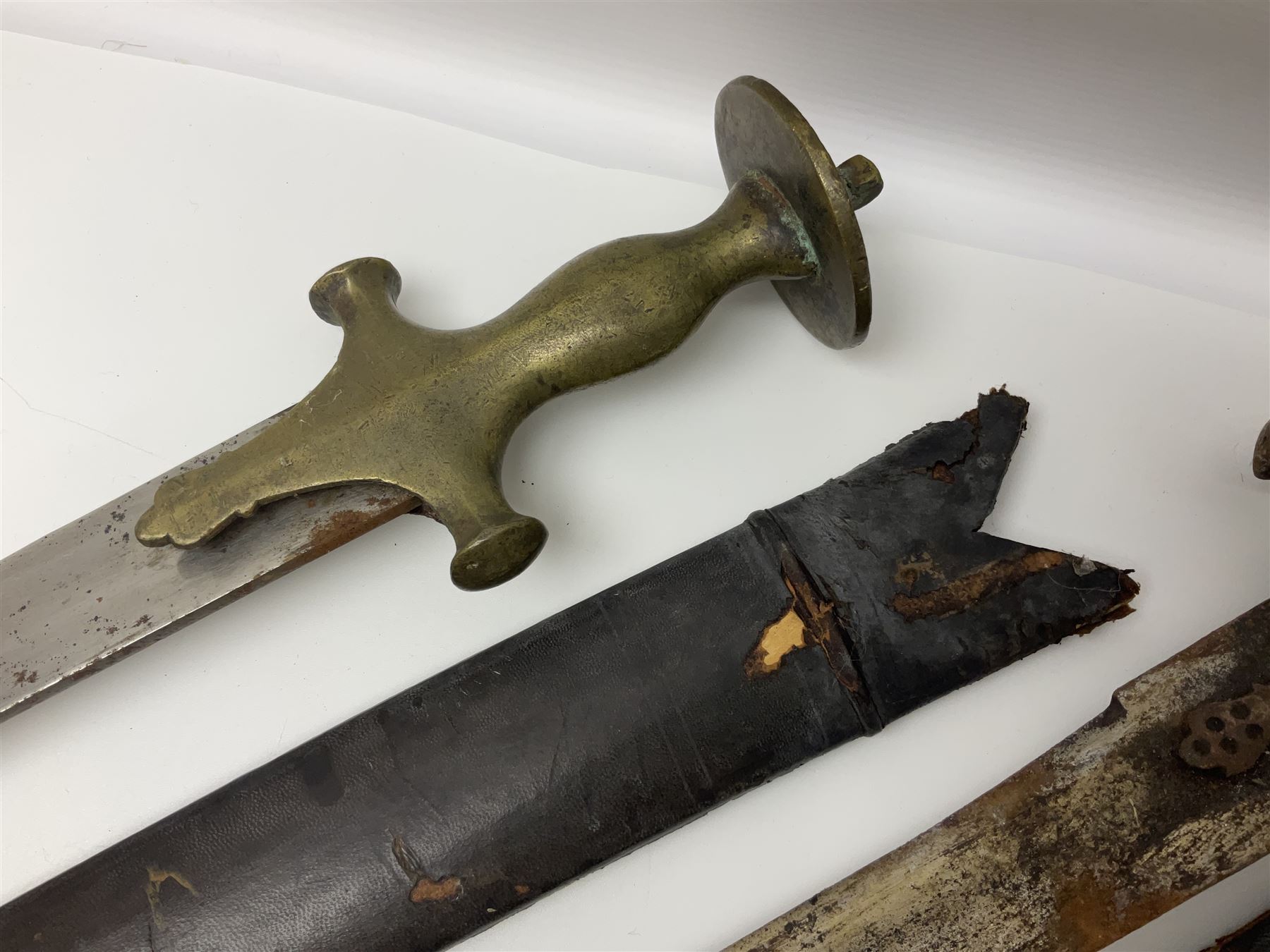 Four Indian tulwar swords; three with cast brass hilts and one with iron hilt; longest blade 81cm; all with scabbards (4)