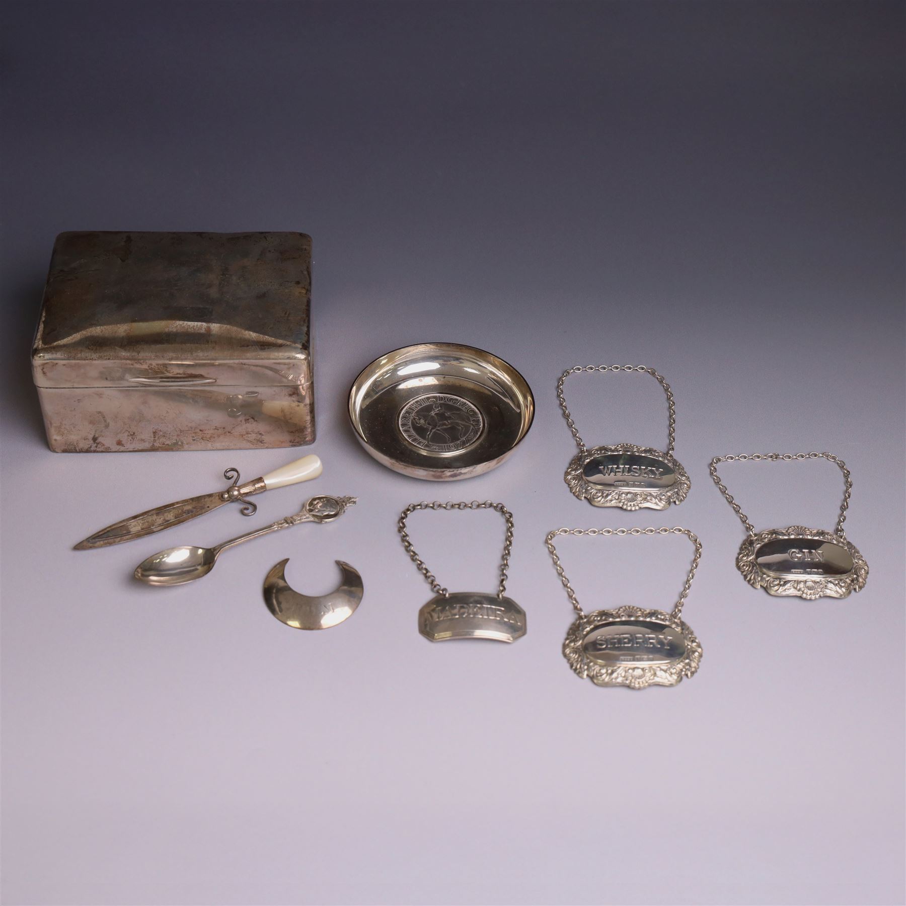 Group of silver, comprising silver mounted cigarette box, five decanter labels, page turner, commemorative teaspoon and a commemorative pin dish set with coin, all hallmarked