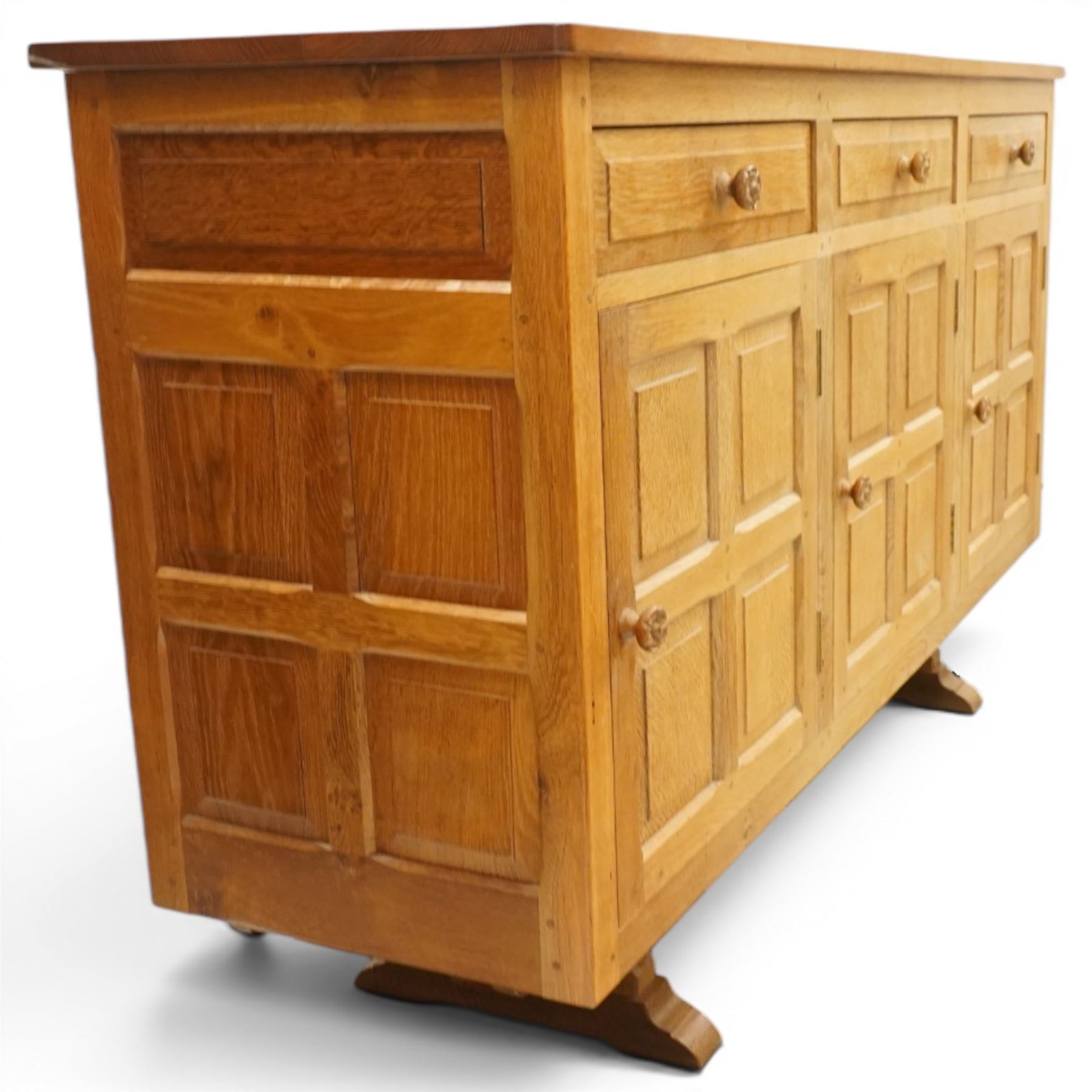 Beaverman - 1980s adzed oak sideboard raised on a trestle base, three drawers over three cupboards with Yorkshire Rose carved handles, fielded panelled sides and front, with carved Beaver, by Colin Almack of Sutton near Thirsk