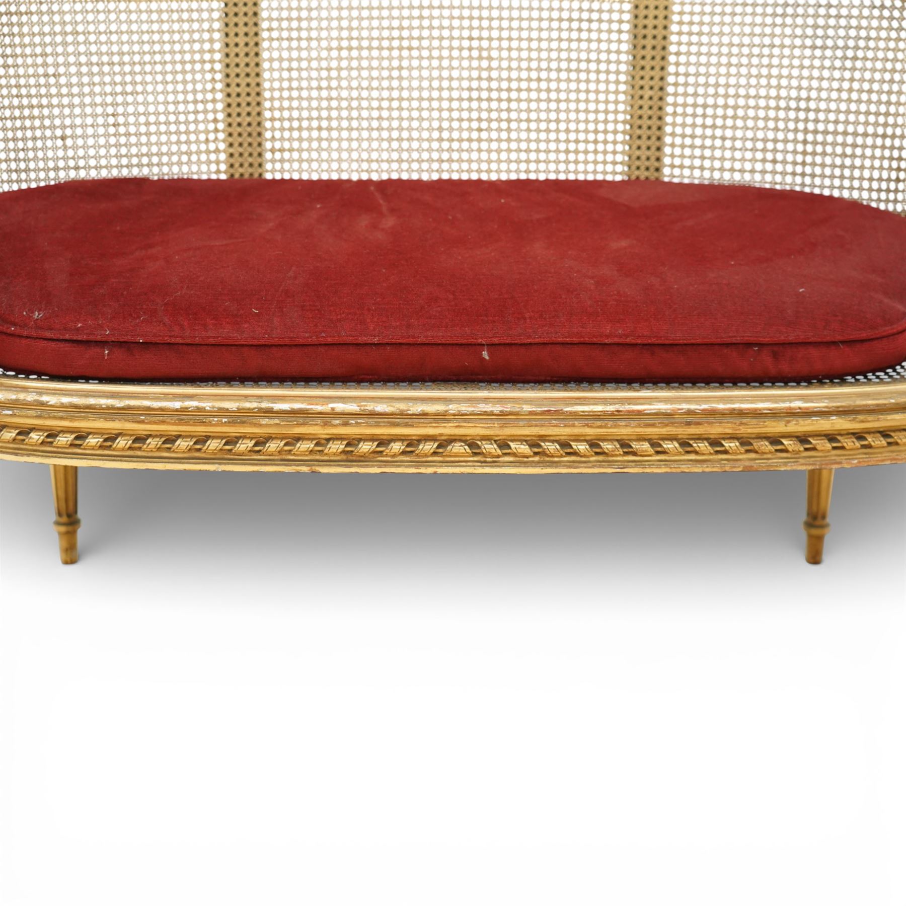 19th century giltwood and gesso settee, with shaped crest rail centred by carved floral detail, the cane back with vertical divisions, upholstered seat with loose cushion, raised on fluted tapering legs
