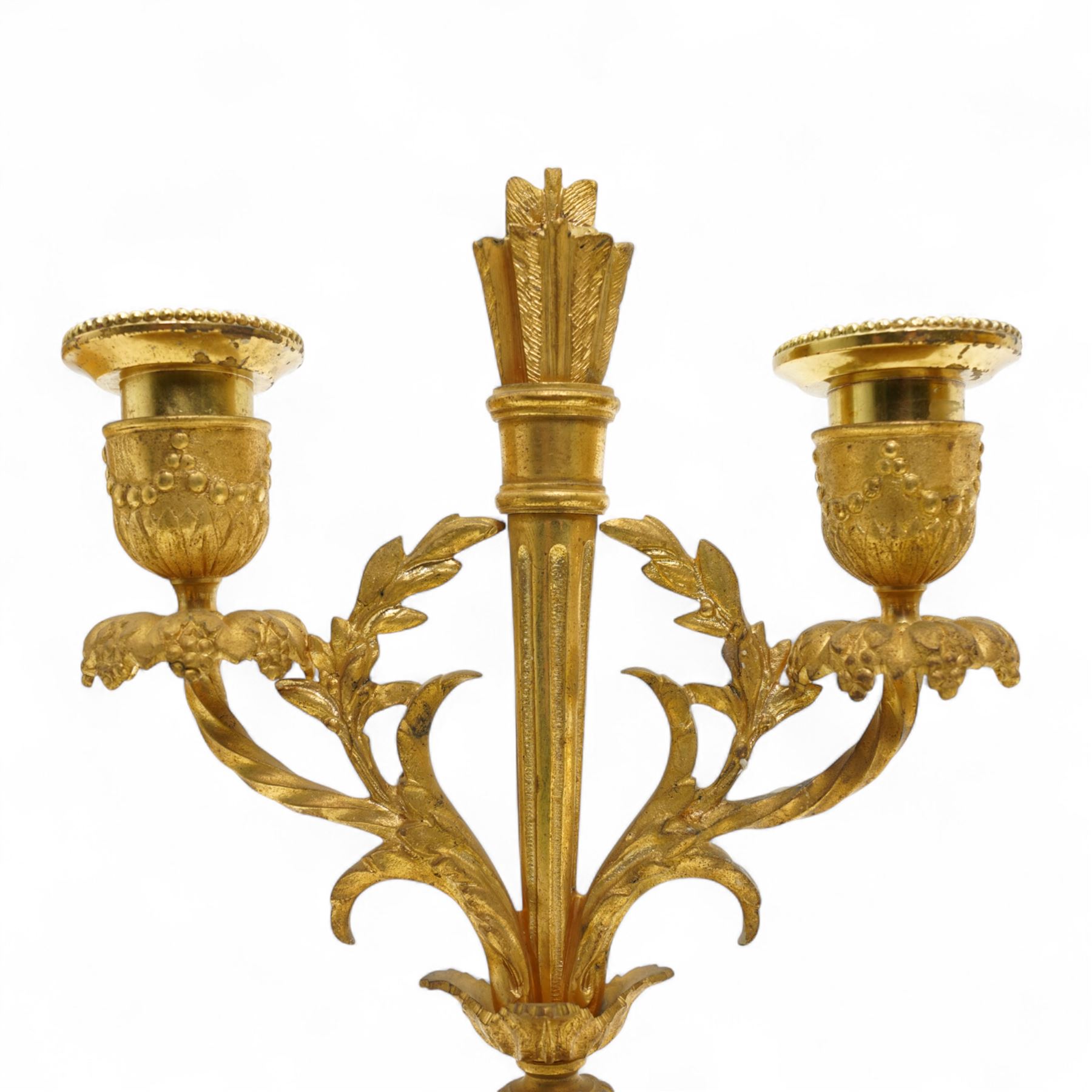 French-Ormolu and white marble mantle clock with garnitures, c 1910, with a white enamel dial and Arabic numerals, indistinct signature, pierced gilt-metal hands and minute markers, 8-day twin train countwheel striking movement, sounding the hours and half-hours on a bell, with a matching pair of two light candelabra. With pendulum and key.