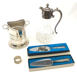 A clear glass claret jug with silver plated mounts, the bulbous body with cut decoration, curved acanthus capped handle and bud modelled finial, H30cm, together with a silver plated wine coaster or bottle holder, a silver napkin ring hallmarked E F Braham Ltd, Birmingham 1930, and two silver handled cake servers, hallmarked Harrison Brothers, Sheffield 1972/1982.
