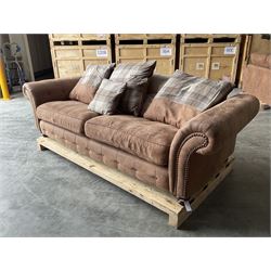 Four seat sofa upholstered in studded and buttoned suede fabric, scatter cushion back, scrolling arms, turned supports