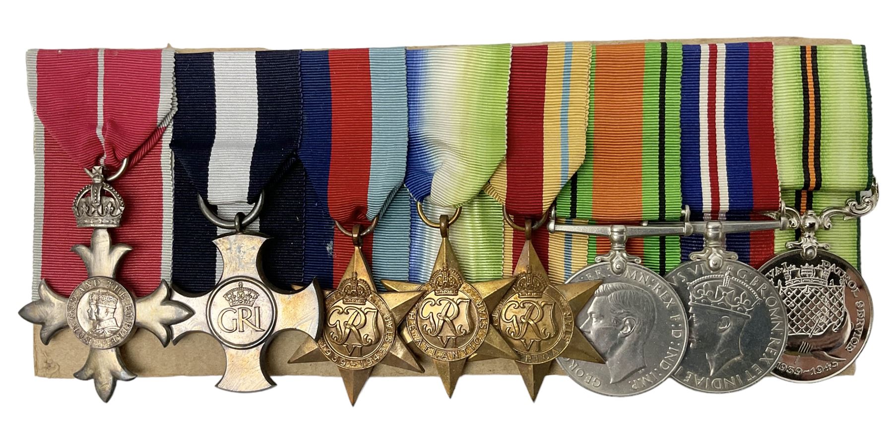 WW2 Royal Naval group of eight medals comprising OBE, hallmarked silver Distinguished Service Cross inscribed verso Lieut. J.R. McCluskie RNVR 1945, 1939-1945 Star, Atlantic Star, Africa Star, 1939-1945 War Medal, Defence Medal and Royal Naval Patrol Service Medal inscribed Lieutenant J.R. McCluskie Royal Naval Patrol Service; with seven original photographs of a sea battle 27th November 1940 against the Italian Fleet and another photographic postcard of Sir Stafford Cripps arriving on board one of the vessels.