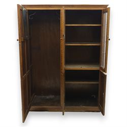 Edwardian oak glazed cabinet, moulded cornice above a panelled front and sides, fitted with lead glazed doors enclosing shelved interior, left side full length cupboard converted to enclose a gun cabinet, on a plain plinth base 