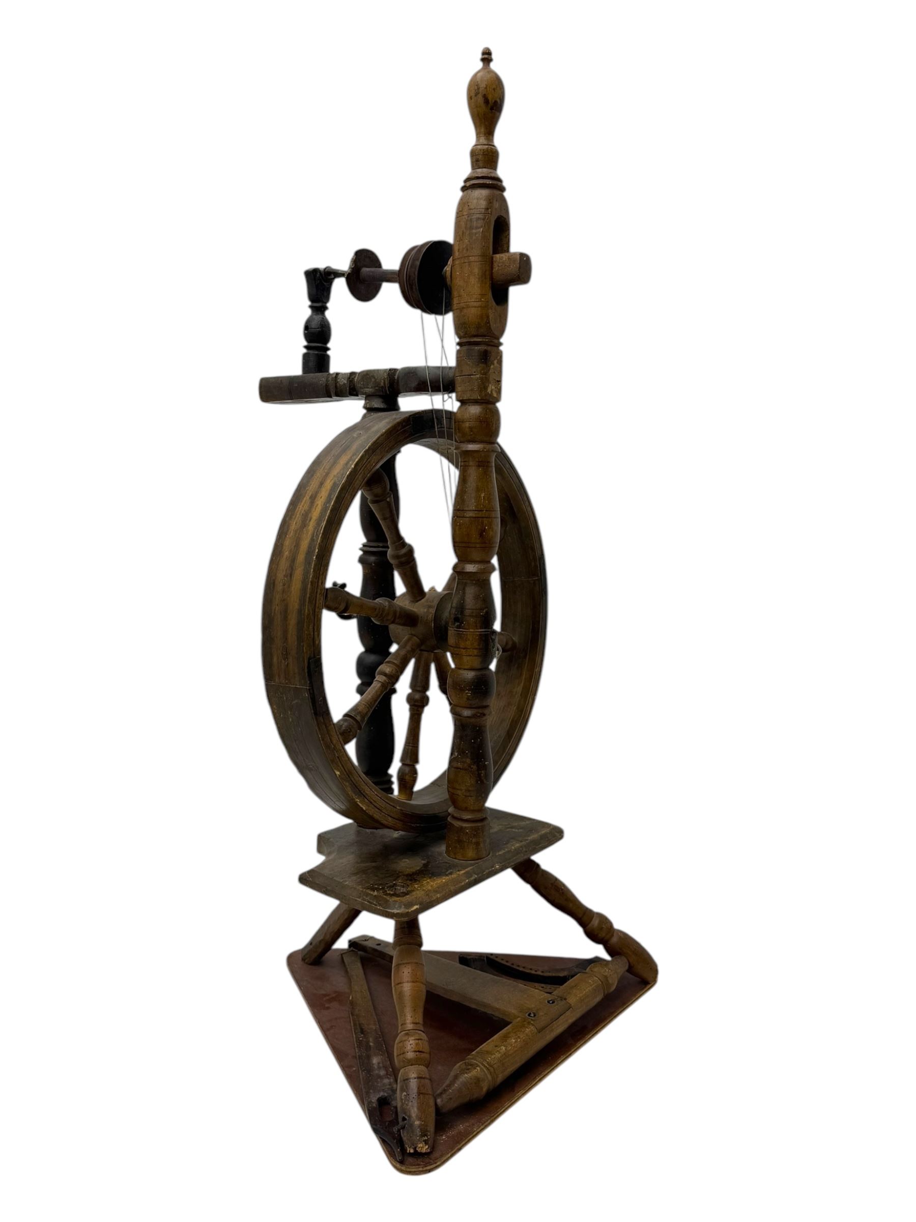 Late 19th century turned beech spinning wheel, upright form with single treadle, triangular base, and a flyer and bobbin assembly surmounted by a turned finial.