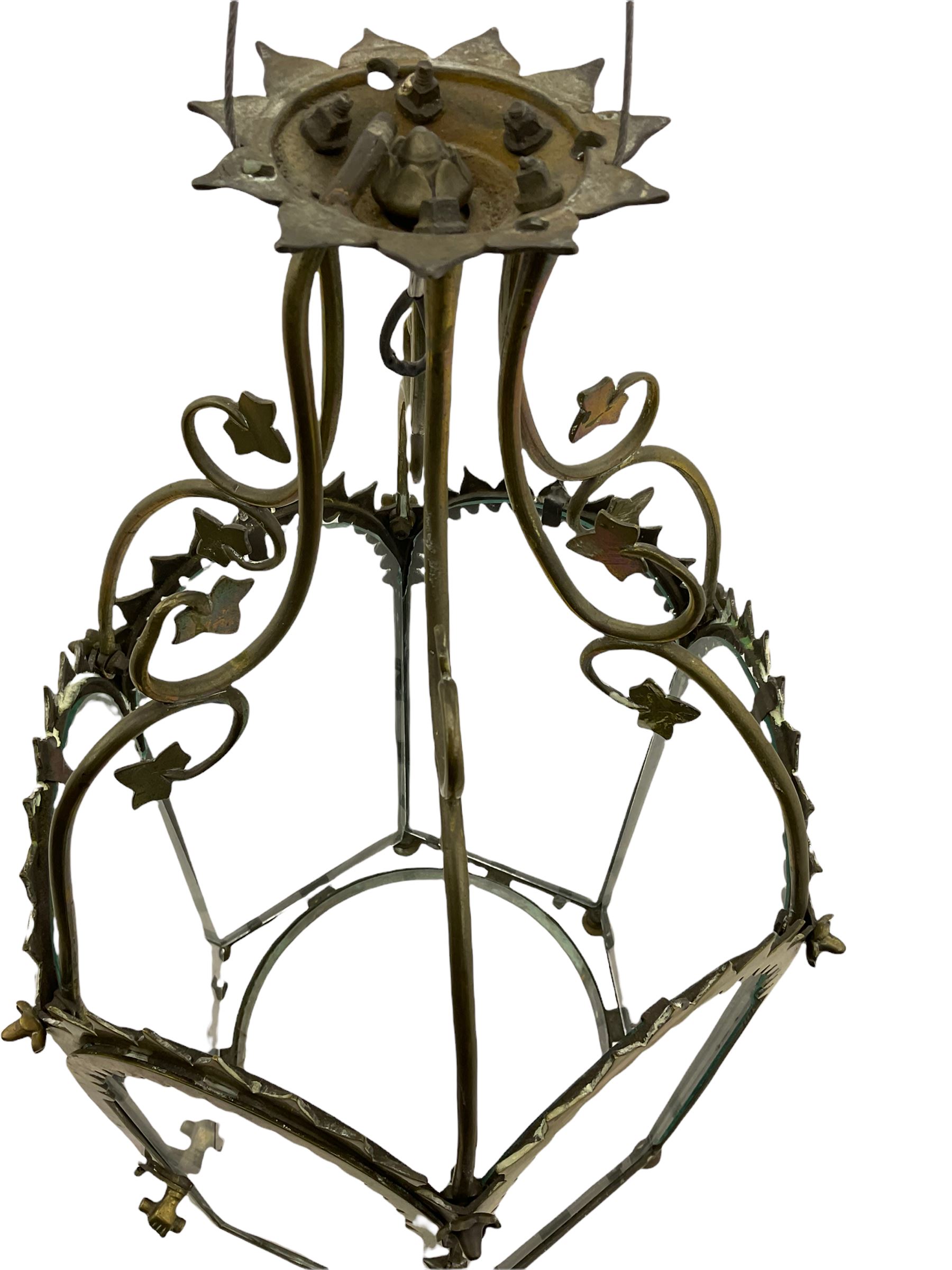19th century brass and clear glass hexagonal hall lantern, with scrolling wire work open domed top over six arched panels, including a hinged door, the base enclosed with a circular glass panel on turned feet, H64cm