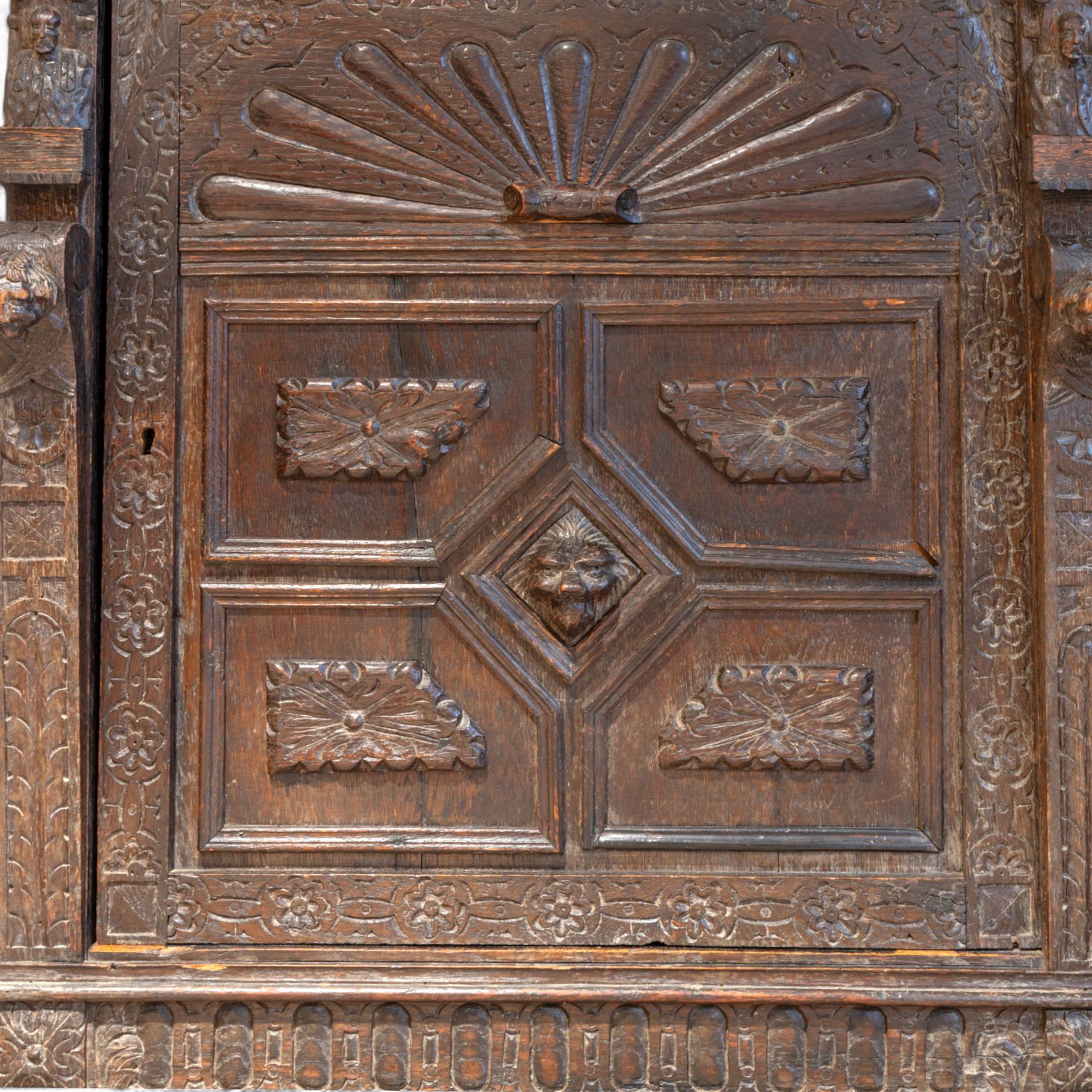 French carved oak cabinet in the Renaissance revival style, cornice carved with scrolling acanthus flanked by lion mask ring terminals, above glazed door with scroll supports over a carved panelled cupboard section with radiating shell motif and geometric quarter panels with foliate ornamentation, raised on a moulded plinth base 