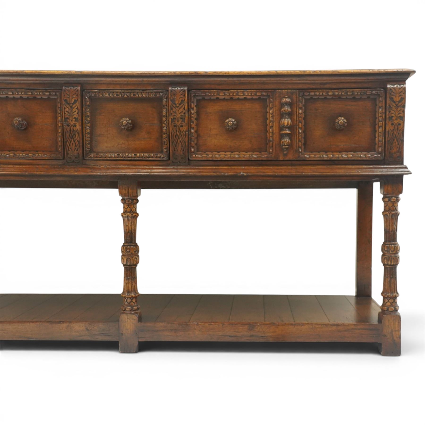 Titchmarsh & Goodwin - Tudor oak dresser base, three drawers flanked by foliate carving and carved wooden knobs, on turned and carved supports, united by a full length undertier