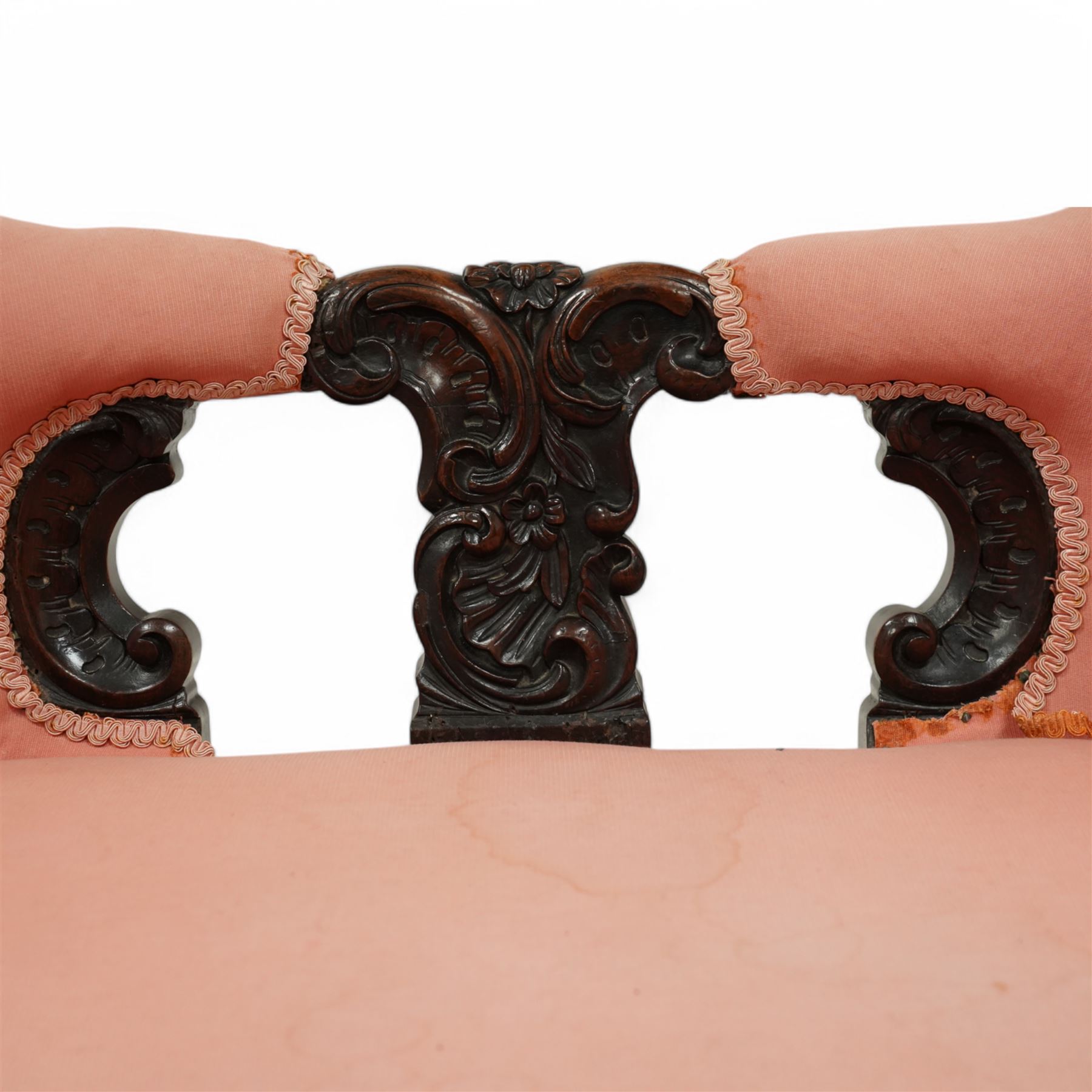 Mid-19th century carved rosewood double-ended settee, double spoon back with central splat carved with C-scrolls and shells, upholstered in pink buttoned fabric, scroll carved arm terminals on shaped supports, on leaf and flower head carved cabriole feet 