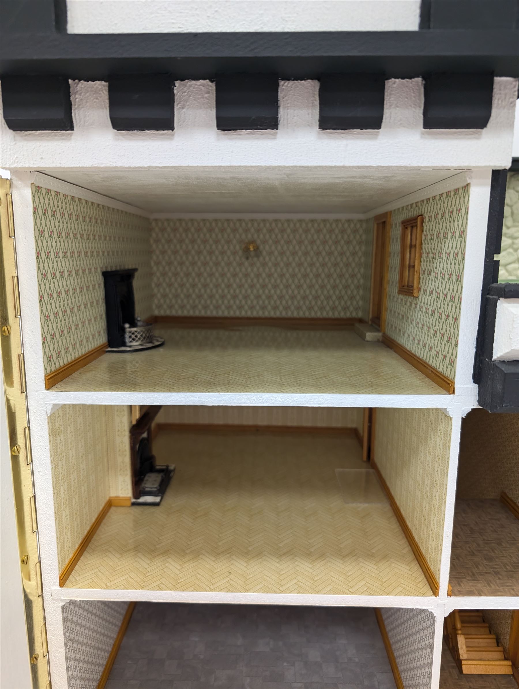 1:24 scale four-storey tudor-style dolls house, with black and white exterior, balcony garden, glazed panelled windows and wooden shingle roof, with decorated interior and wired fireplaces and lighting, H65cm, W58cm, D31cm, 