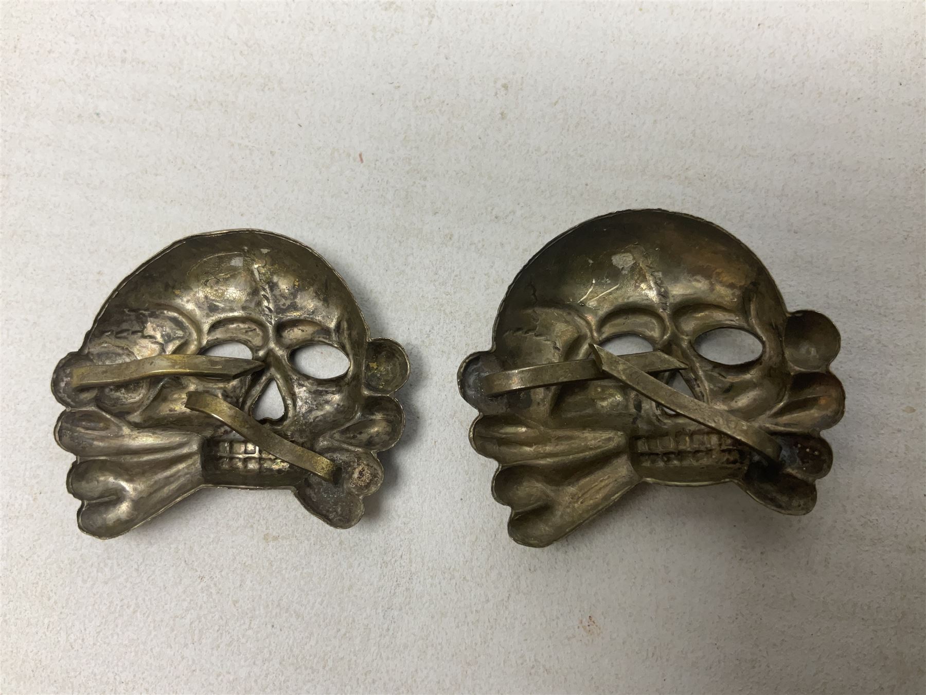 Two WW2 German 'SS' visor cap skull badges and another later; and visor cap eagle insignia (4)