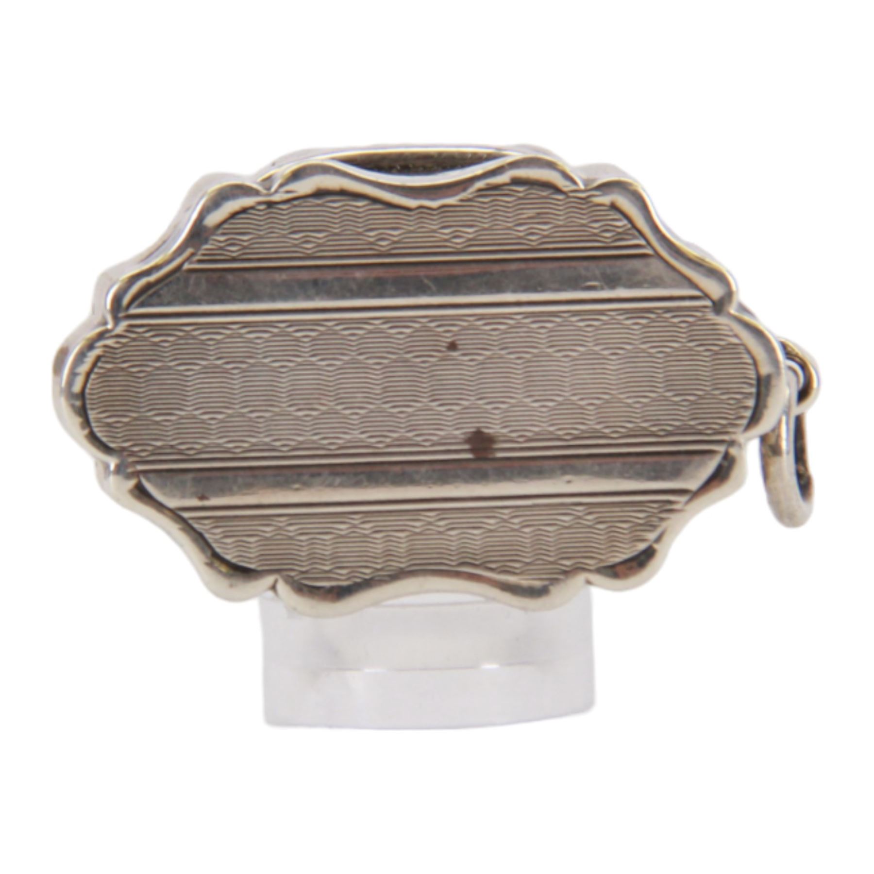 Victorian silver vinaigrette, of oval form with shaped edge, decorated throughout with engine turned bands, the hinged cover with vacant C scroll panel opening to reveal a foliate pierced grille and gilt interior, hallmarked George Unite, Birmingham 1857, L3.5cm