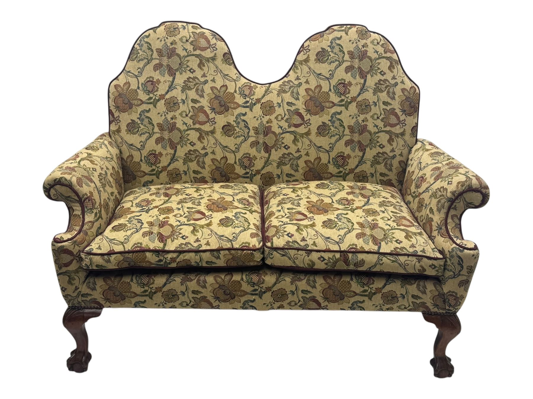 Mid-20th century William and Mary design two-seat sofa, upholstered in floral patterned fabric with contrasting piping, featuring camel-shaped back and scroll arms, on cabriole supports