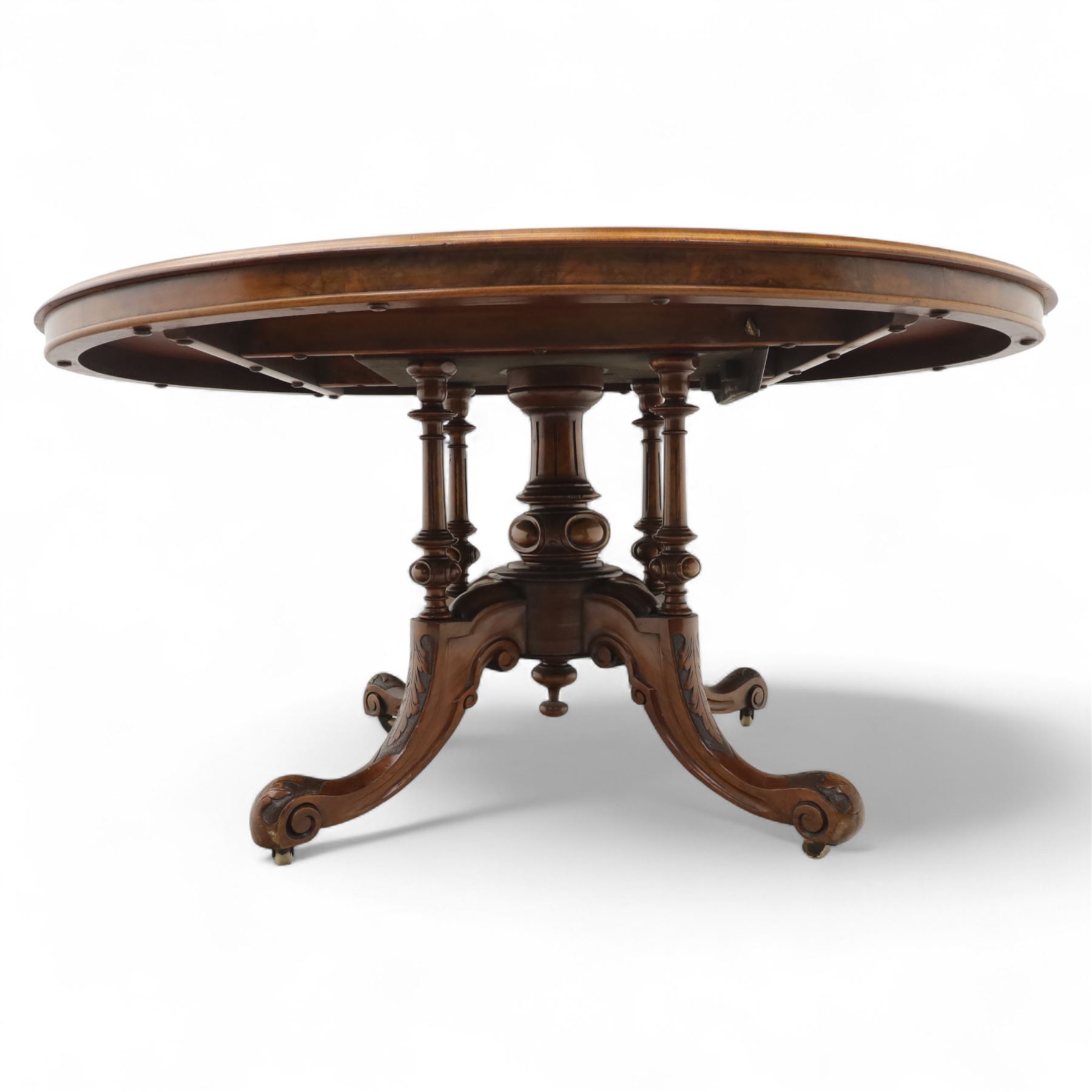 Victorian inlaid burr-walnut and marquetry oval centre table, quarter veneered tilt-top with scrolling foliate and floral marquetry reserves on a turned carved column with clustered supports raised on four out-swept scroll legs on ceramic castors  