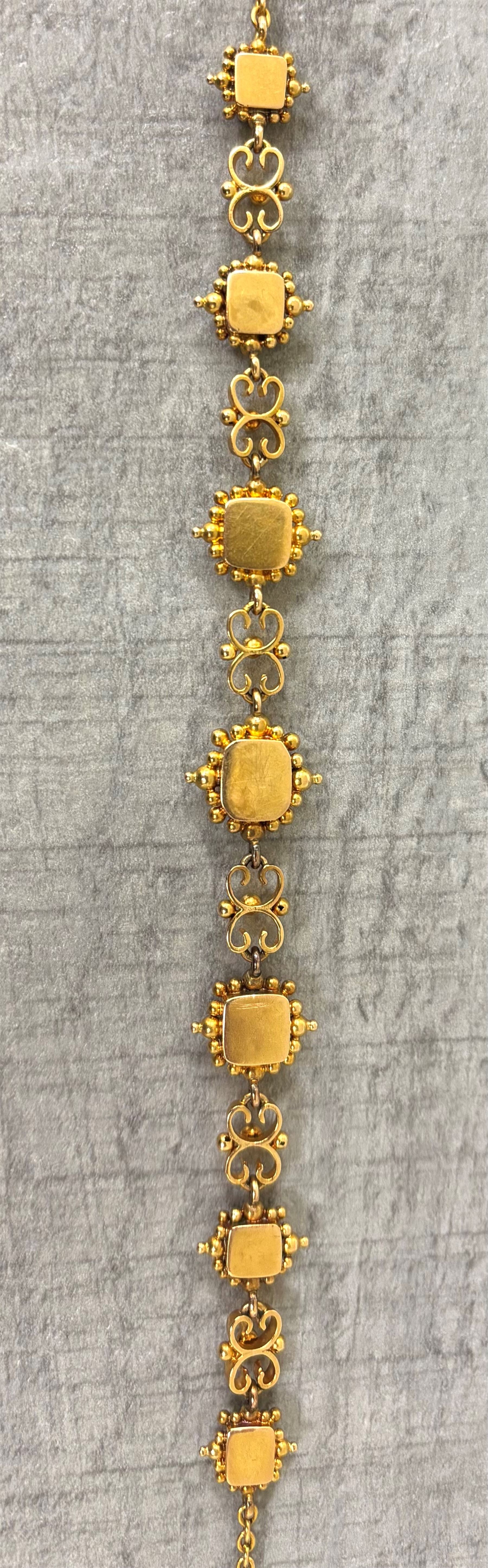 19th century gold emerald necklace, seven closed back octagonal cut and square cut emeralds, surrounded by a fancy bead setting, each spaced by a pierced scroll and bead design link, to a cable link chain necklace, with The Gem & Pearl Laboratory report