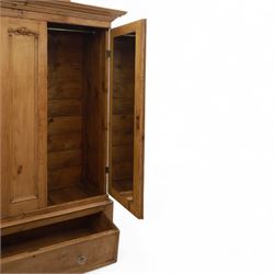 Late 19th century pine wardrobe, with stepped cornice over triple panelled doors, applied foliate carvings to outer panels, raised over a separate pine plinth drawer with moulded facia and twin glass pulls
