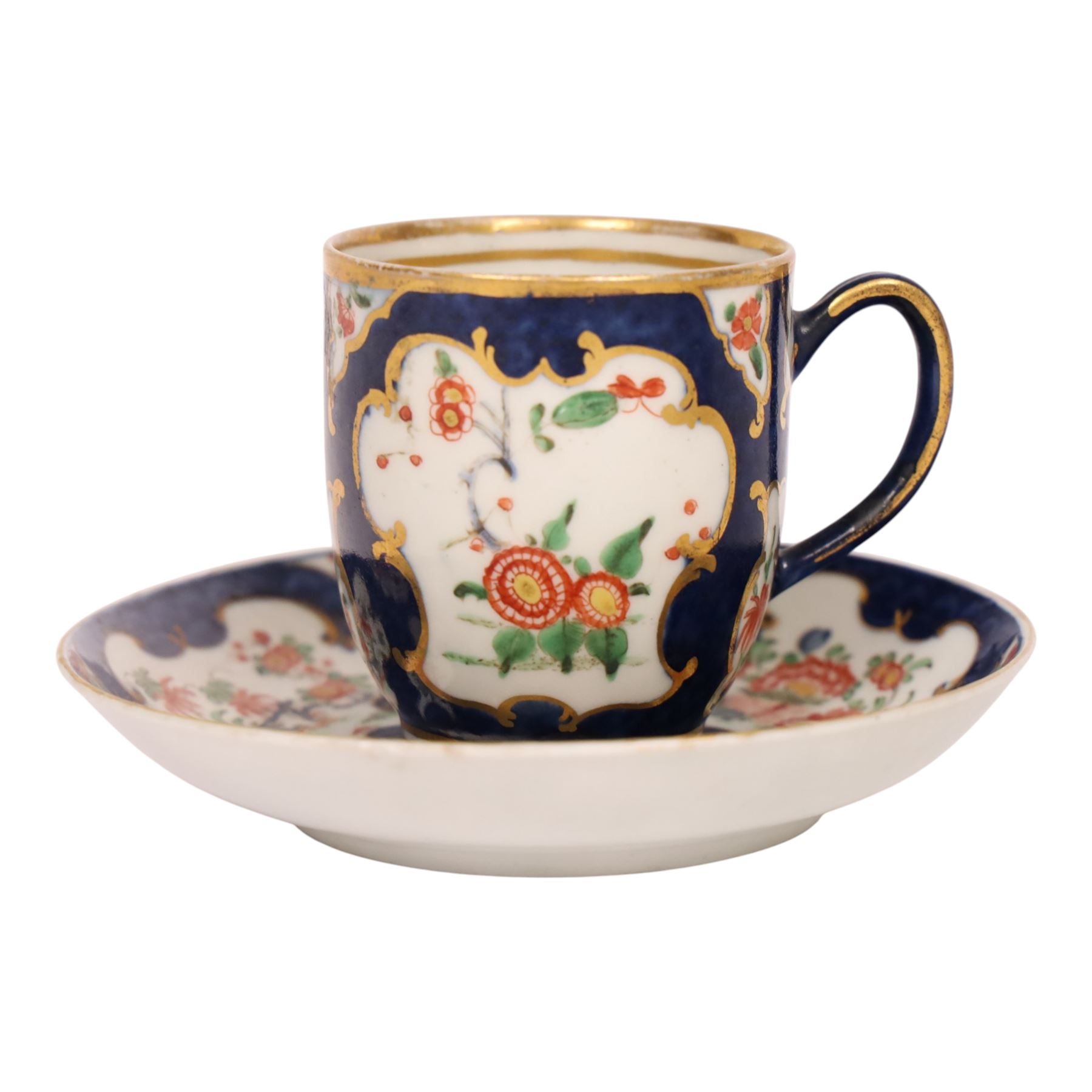 18th century Worcester coffee cup and saucer, circa 1770,  painted with shaped panels of chrysanthemums and banded hedges on a blue scale ground with gilt detail to the rim, mark beneath, H8cm 