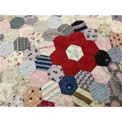 19th century patchwork quilt, hand stitched from hexagons of various materials including printed patterned and floral examples, featuring repeating large central hexagon to centre, the top and bottom with thick panel red jacquard border, the sides bordered with plain red fabric, lined with panels to reverse, 180 x 190 cm