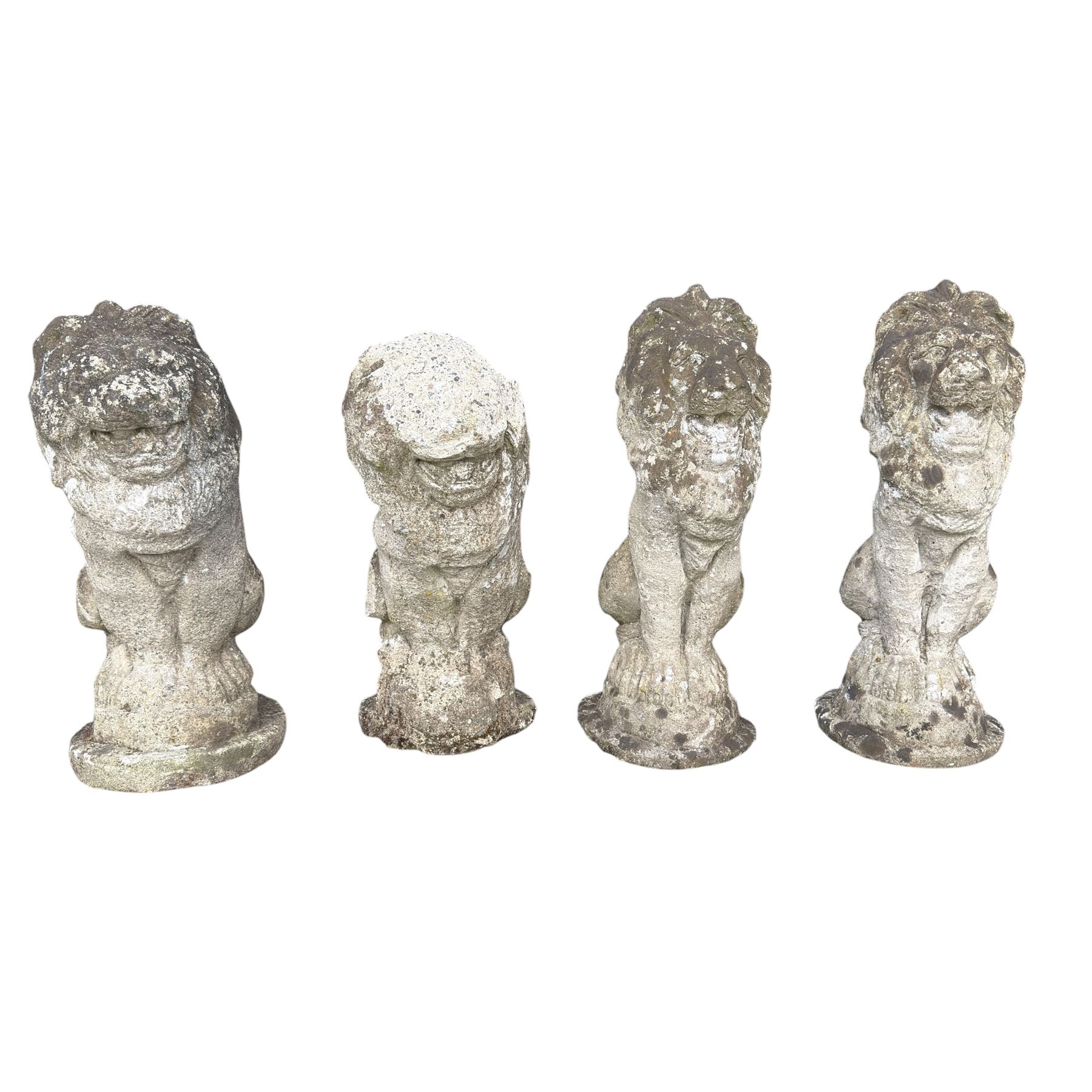 Four weathered cast stone lions in seated poses
