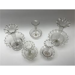 Four Victorian clear glass epergnes, with single frilled trumpet above a frilled bowl and circular foot, largest example H24cm, smallest example H15.5cm, together with a further Victorian clear glass epergne with etched foliate decoration to trumpet and bowl. 