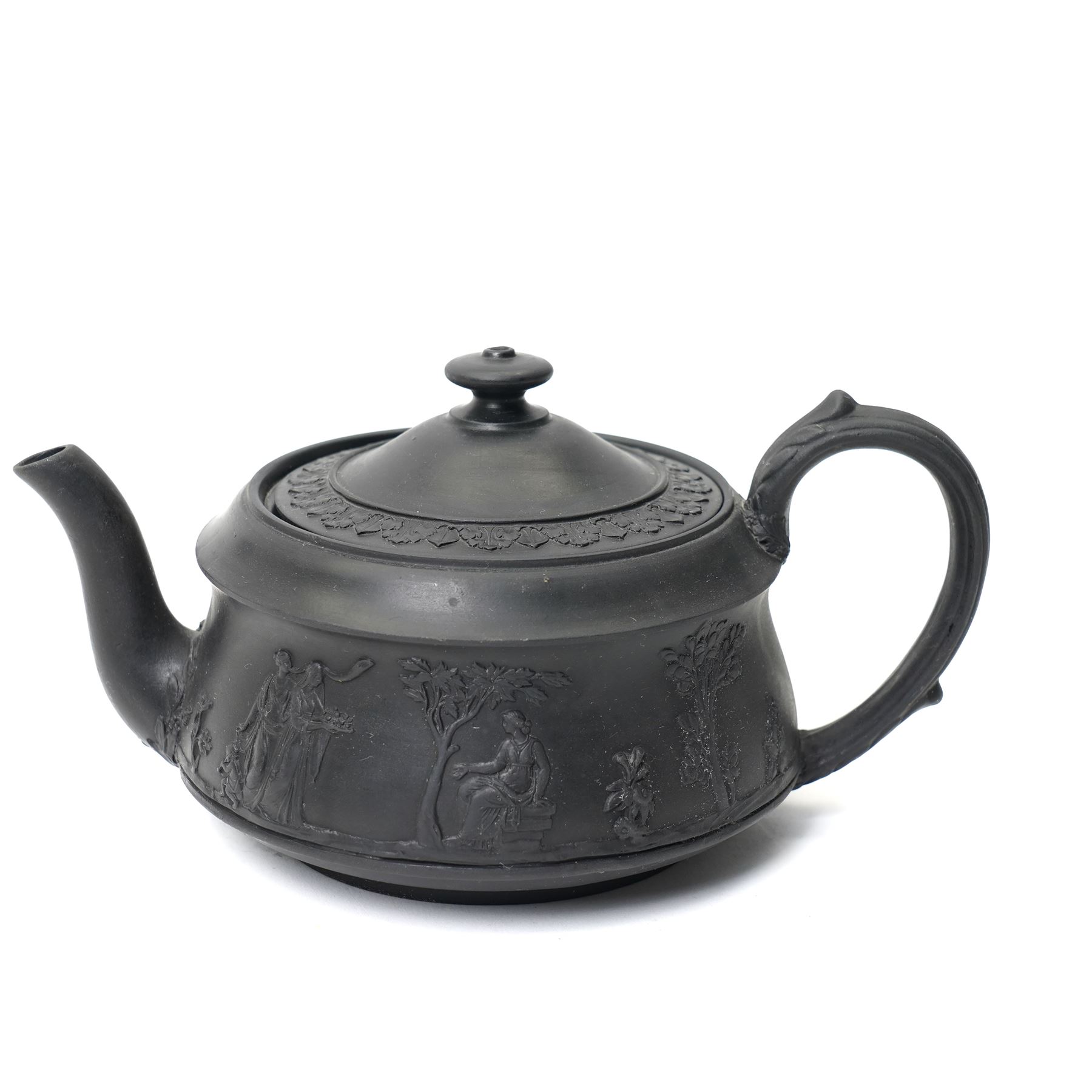 Four pieces of 19th century Wedgwood black basalt ware, c.1875, comprising larger and smaller jug, covered sucrier and teapot, each decorated with classical scenes in high relief, larger jug H13cm