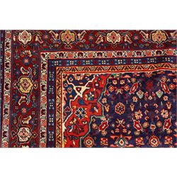 West Persian Mahal hand-knotted carpet, indigo field with central stylized angular medallion issuing an all-over Herati-inspired lattice of floral sprays, rosettes and geometric vinery in tone soft madder red, ivory and soft blue, principal border decorated with stylized palmettes, and angular vine motifs, flanked by multiple guard borders, with cotton fringe ends 