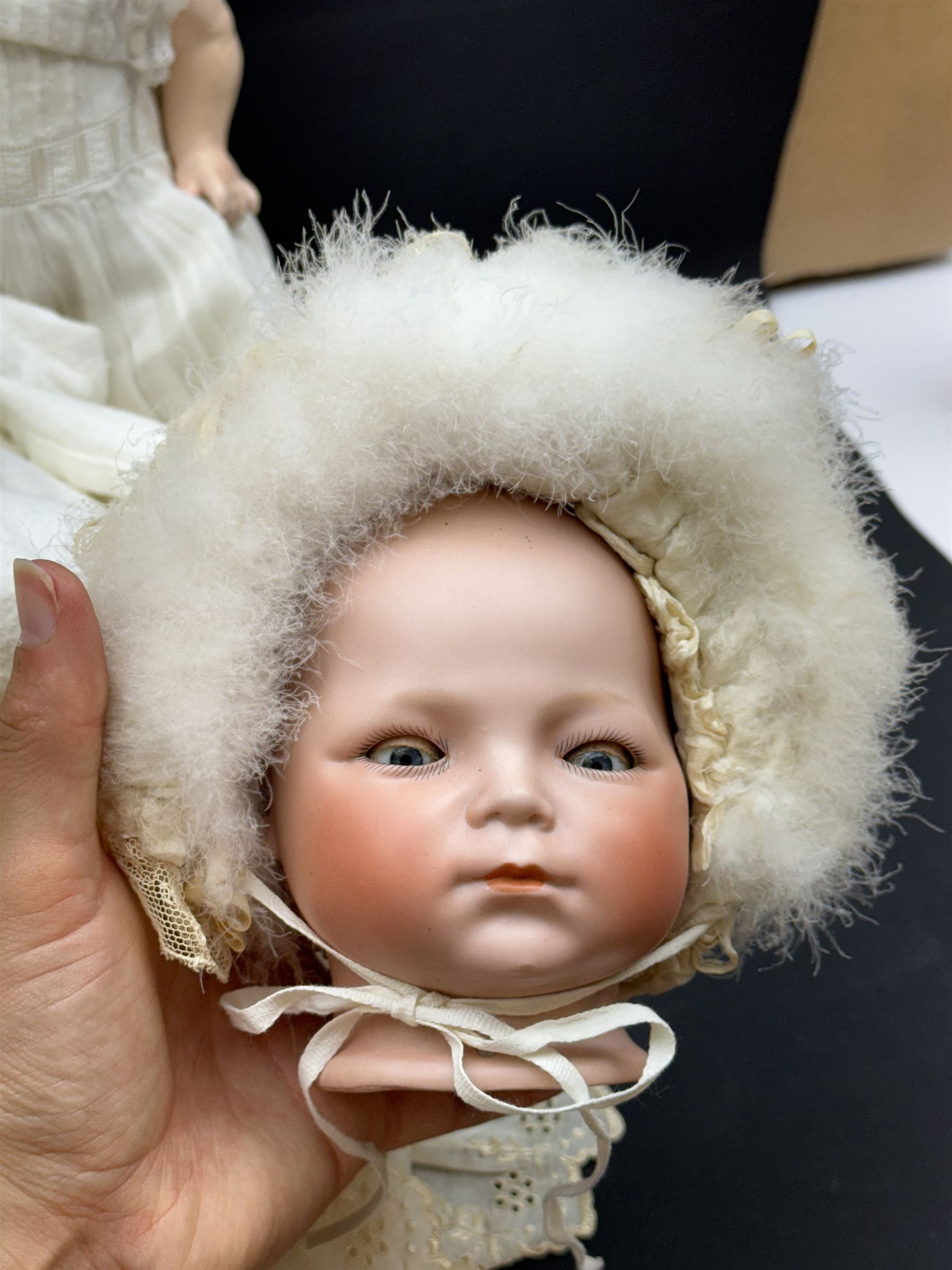 Two German bisque head dolls, to include a Franz Schmidt example with blue glass eyes and an Armand Marseille 590 example with applied hair, together with a Schoenau & Hoffmeister bisque doll's head, pair of doll's hands and a collection of clothing