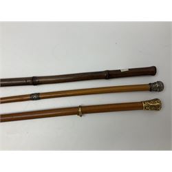 Early 20th century bamboo sword stick with 39cm oblong section blade L85cm overall; and two malacca cane swagger sticks, one with white metal mounts the other with yellow metal mounts (3)