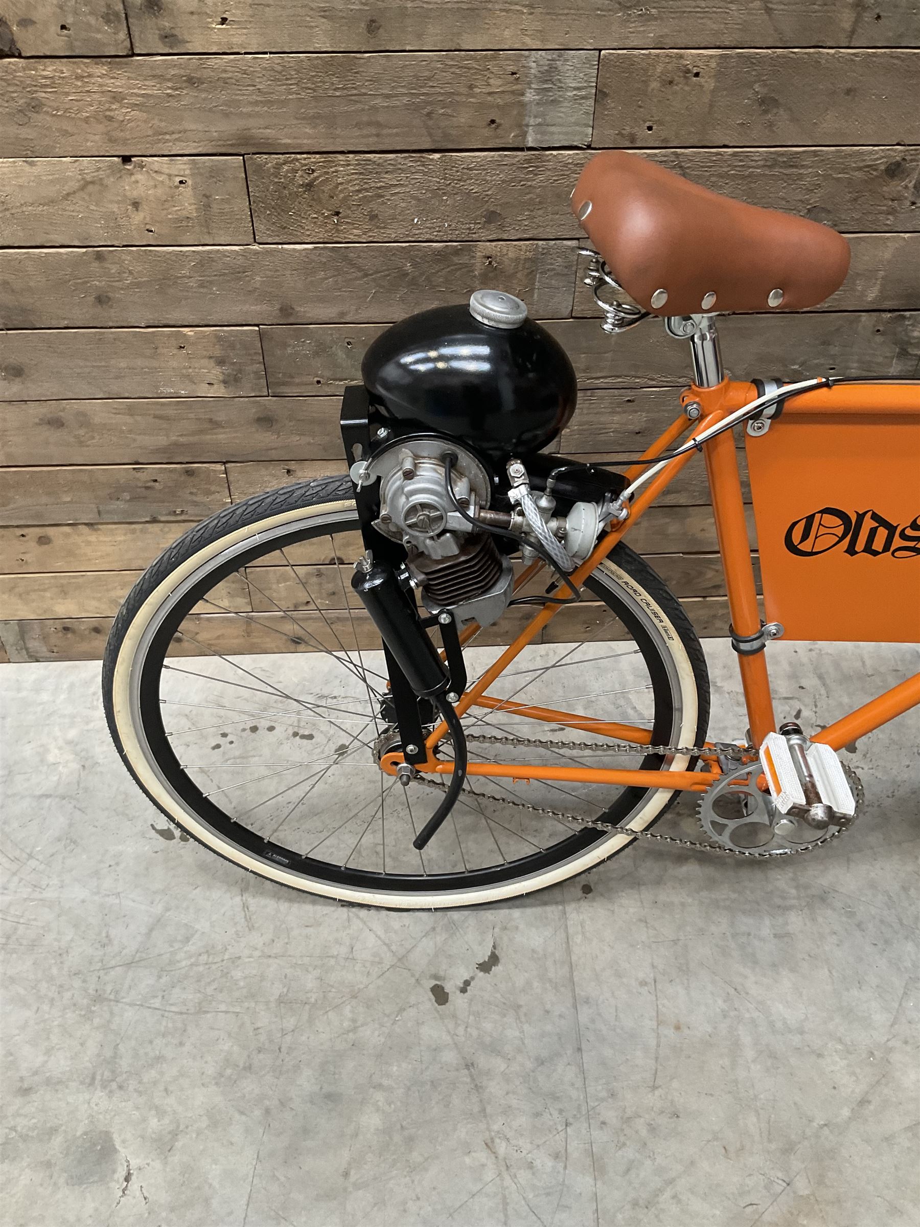 Fully restored vintage advertising bicycle with 2 stroke petrol engine, orange frame, tan leather seat