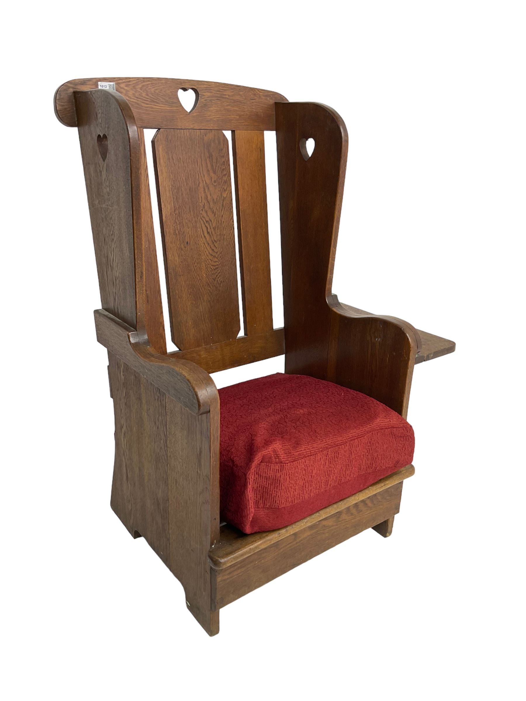 Arts and Crafts design oak reading wingback armchair, high back with pierced heart design, drop-leaf side table to one arm