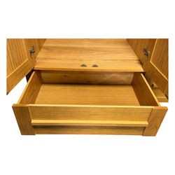 Contemporary light oak triple wardrobe, panelled doors with vertical linear design, left section enclosing hanging rail and single shelf, right section with adjustable shelves, over two drawers, on square stile supports