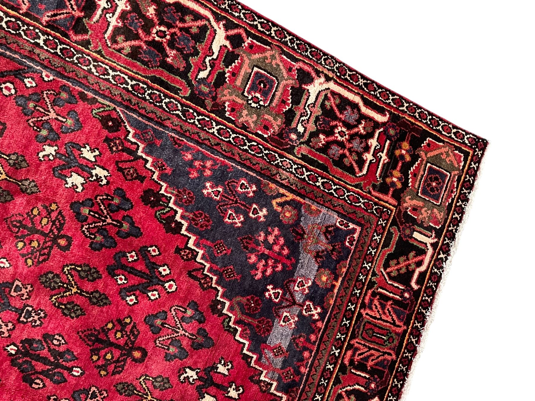 Persian Joshaghan crimson ground rug, stepped lozenge medallion surrounded by repeating foliate lozenge motifs, the border decorated with stylised plant motifs, within geometric guard stripes 