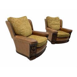 Pair of 1930’s carved oak framed club chairs, upholstered in tan studded leather with beige fabric loose cushions