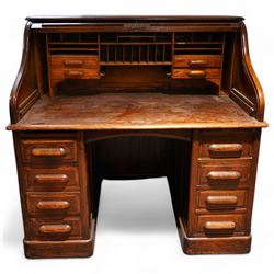 Early 20th century oak twin pedestal roll top desk, tambour roll enclosing small drawers and pigeon holes, fitted with seven drawers, on plinth base 