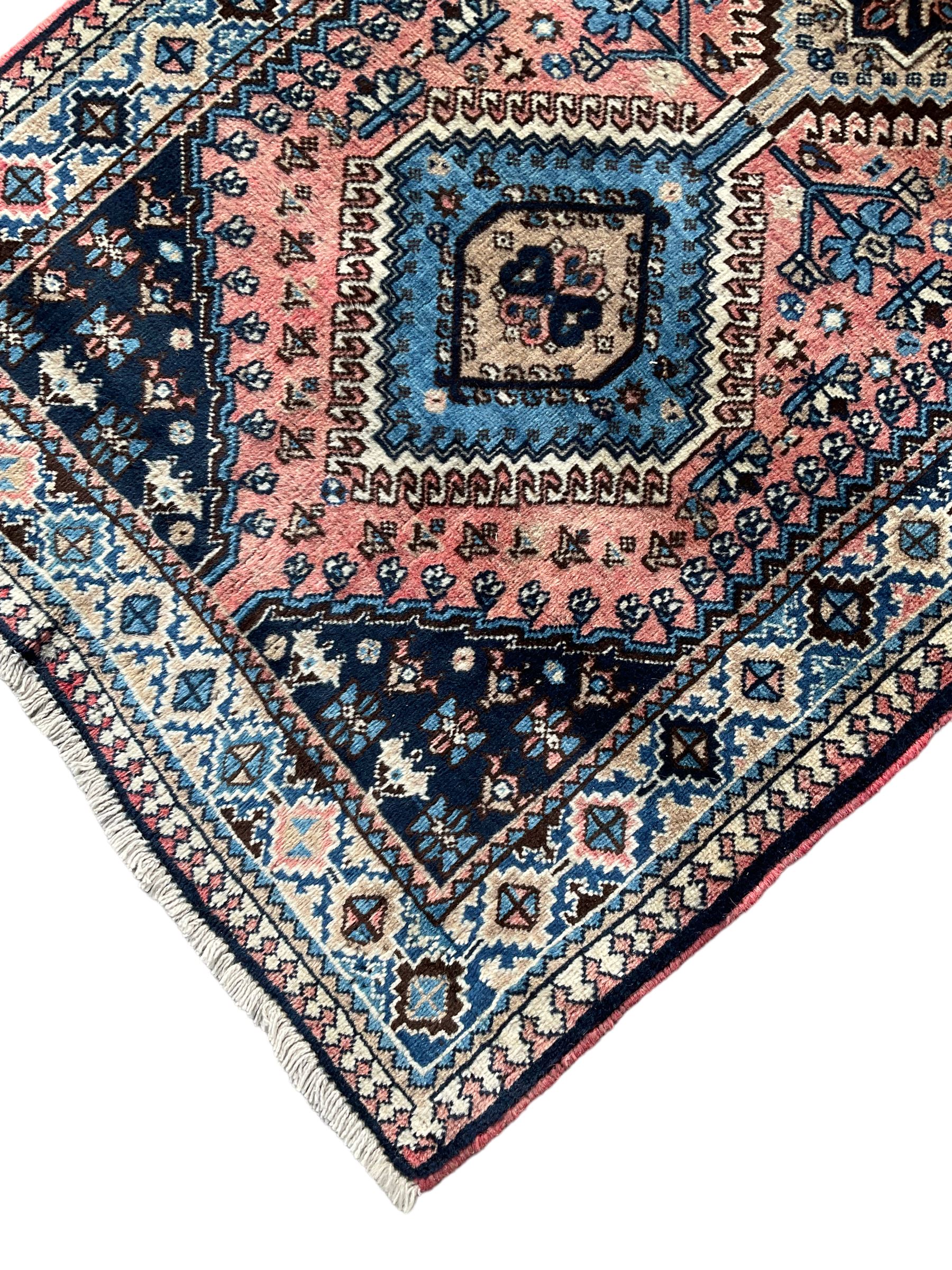 Persian Yalameh coral ground runner rug, the field decorated with seven hooked lozenge medallions surrounded by stylised plant motifs, the indigo spandrels decorated with similar patterns, guarded border with repeating diamond lozenges