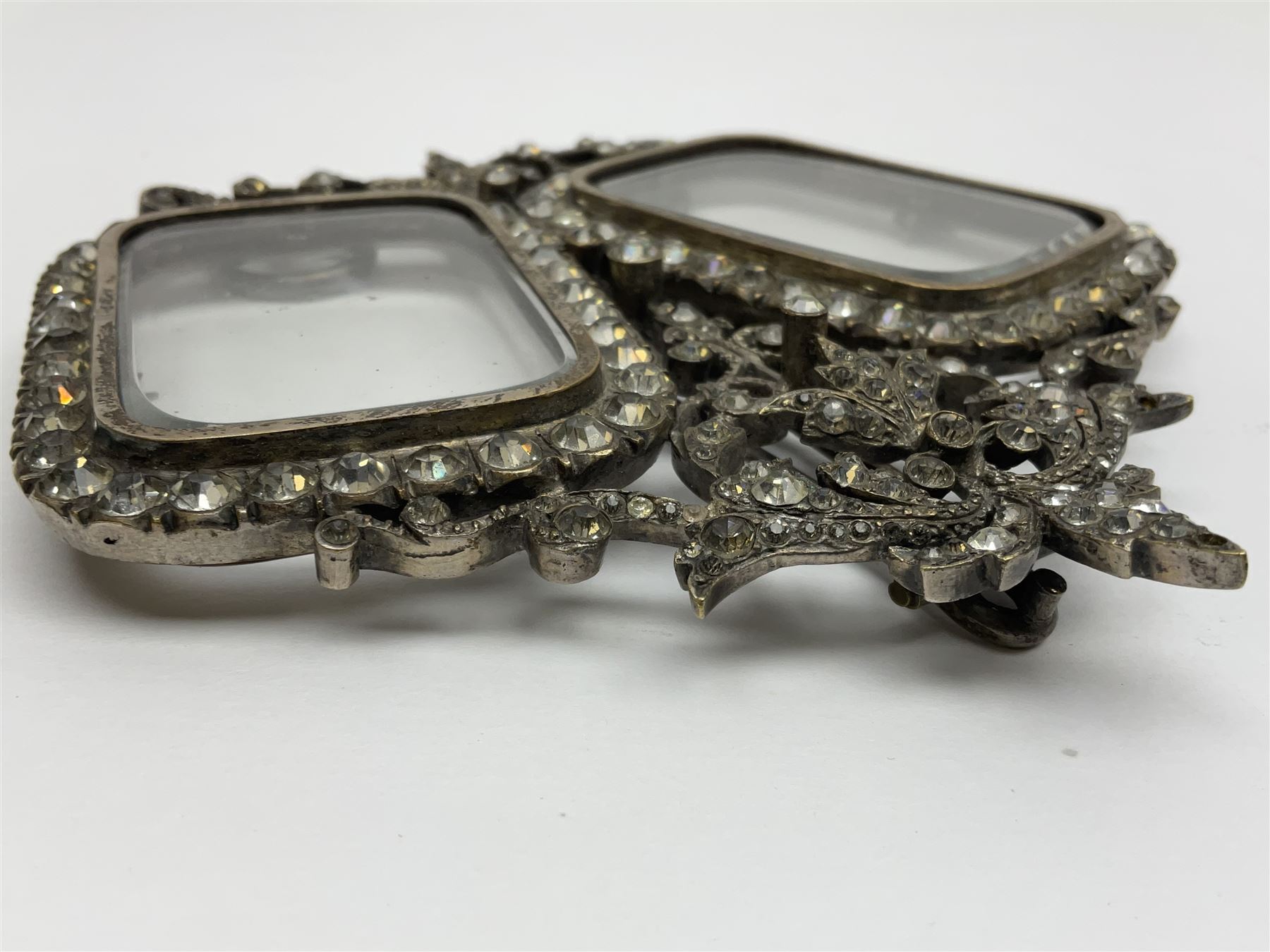 Early 19th century silver plated double photograph frame, each rounded rectangular aperture surrounded by a paste border, with ornate scroll feet and mantling also set with clear paste stones, with easel style support verso, H12cm