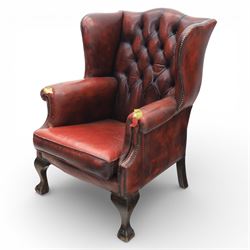 Georgian design wingback armchair upholstered in oxblood leather, the deep button upholstered back with shaped wings and out-scrolled arms, close nailhead trim to the edges, over a loose seat cushion, raised on cabriole front supports terminating in claw and ball feet