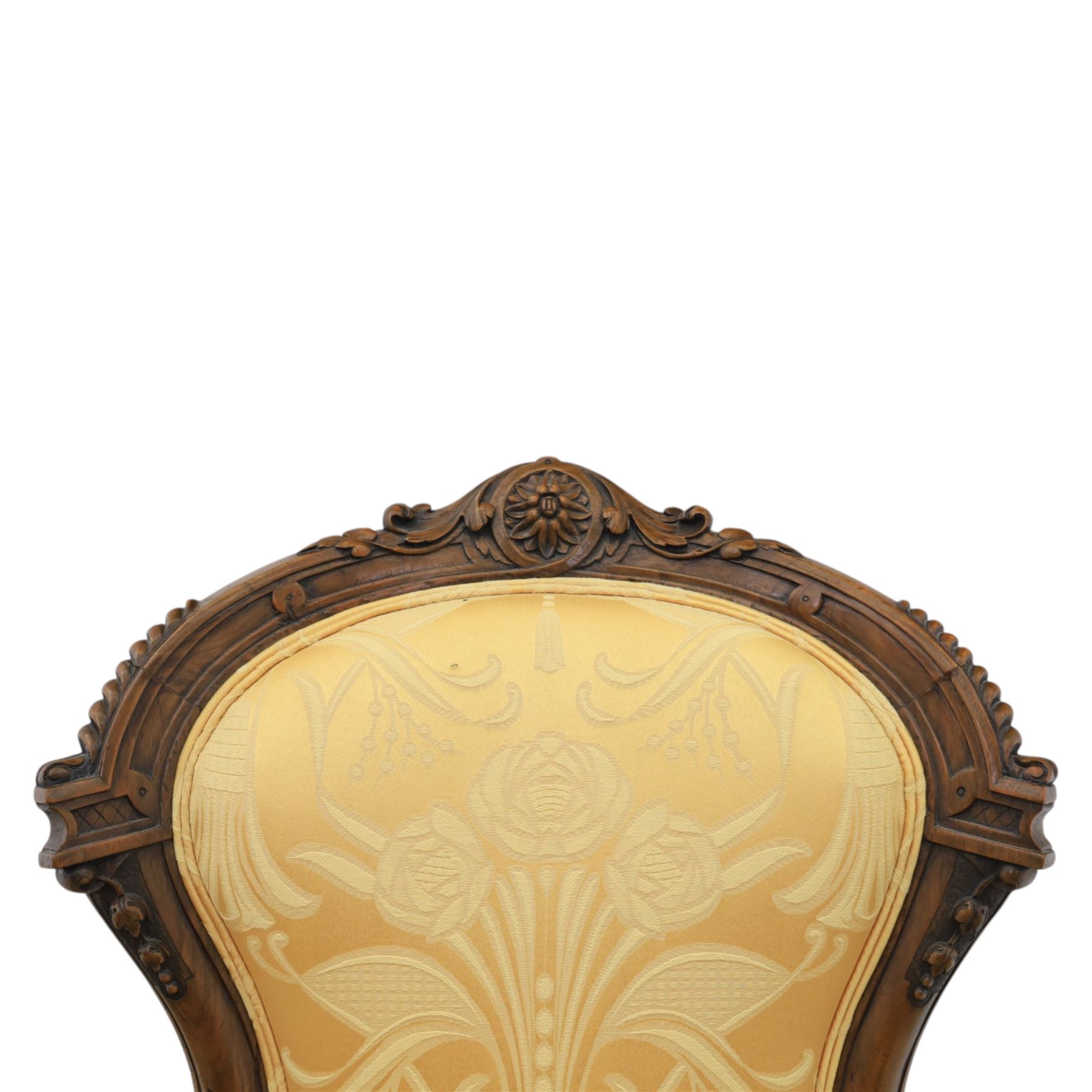 Victorian carved walnut open armchair, shaped and moulded frame with foliate carved cresting rail, upholstered back and seat in yellow damask fabric, scroll arms with padded rests, carved cabriole supports terminating in ceramic castors